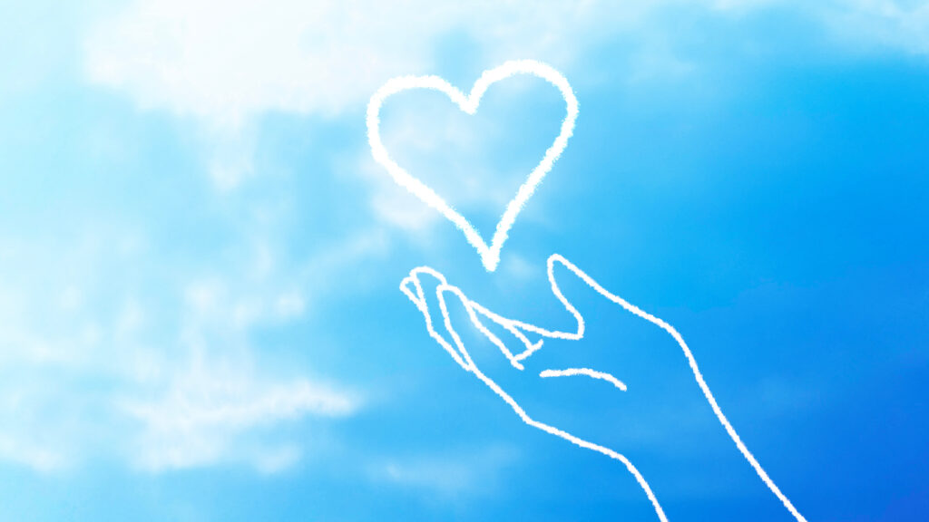 自分をいたわる心を象徴するように、手のひらで大切に守られた光り輝くハートと、開放感のある青空。